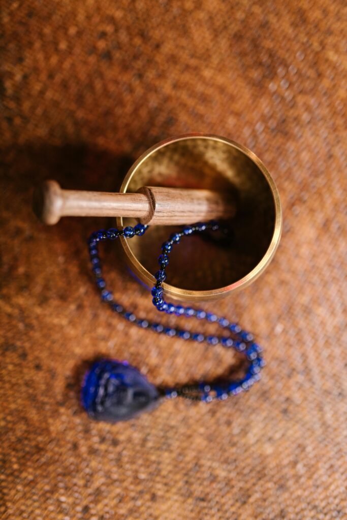 Overhead view of a Tibetan singing bowl with mala beads on a woven mat, enhancing meditation practice.